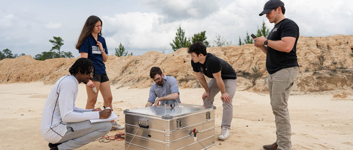 University of South Alabama students, from left, Devon Edinburgh, Paige Palazzo, Matthew Crump, Reed Turner and Luke Andress run though a series of tests on their senior research project at a firing range north of Mobile. 